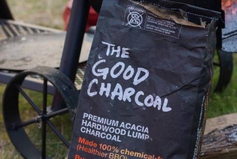 Bag of The Good Charcoal placed near a grill outdoors.