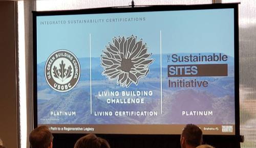 A presentation slide displays three sustainability certifications—LEED Platinum, Living Building Challenge Living Certification, and Sustainable SITES Initiative Platinum—under the heading “Integrated Sustainability Certifications.”