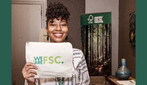 Attendee holds a “We Are FSC” canvas bag and smiles at the camera.