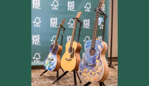 Three decorated guitars on display against an FSC backdrop.
