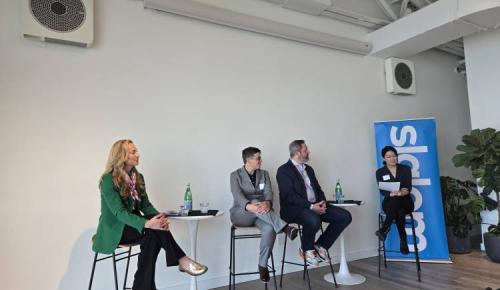 Four speakers sit on stools at the front of a modern conference room during a sustainability panel, with a blue “Slalom” banner in the background.
