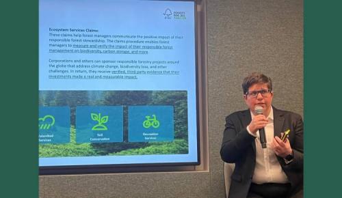 Speaker discusses ecosystem services with a presentation slide behind them.