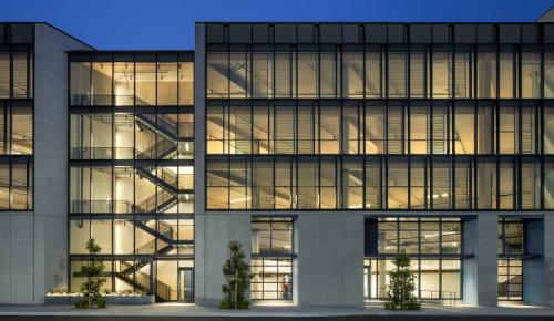 Exterior view of a multi-story glass building illuminated at dusk.