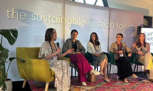 Five speakers sit on stage discussing sustainability at the Sustainable Fashion Forum.